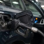 A close-up shot of a car fuel tank showing the refueling process at a station.